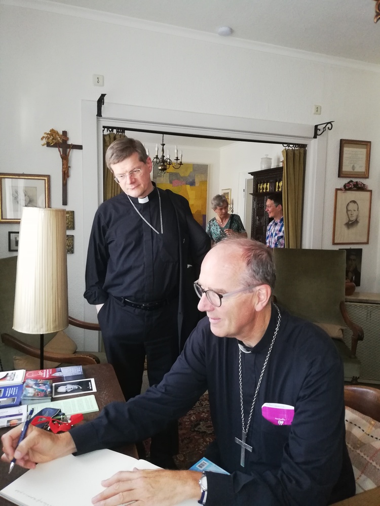 Erzbischof Burger (l.) und Bischof Christory (r.) am Schreibtisch von Franz Stock bei der Eintragung ins Gästebuch (Foto: Margreth Dennemark)